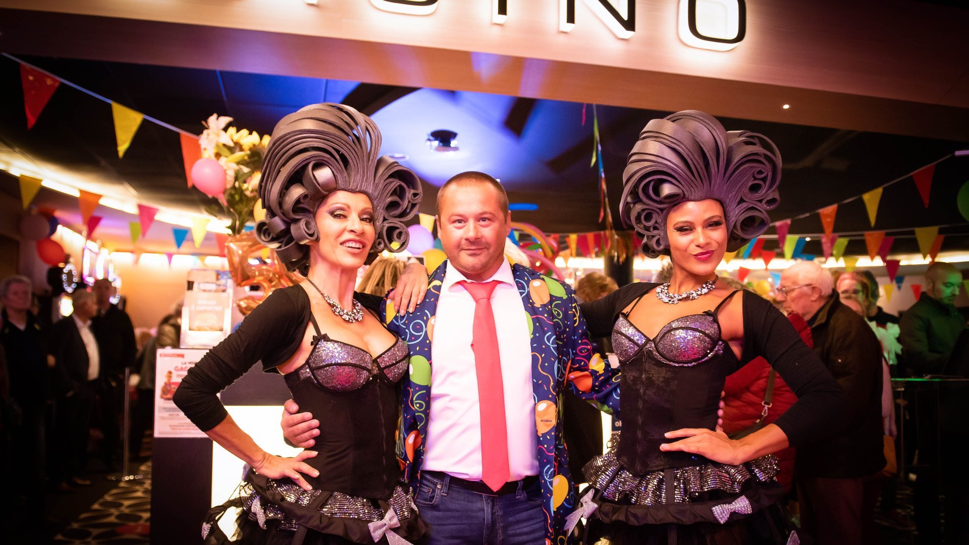Soirée festive au Casino Partouche Agon-Coutainville : un invité entouré de danseuses lors d'un événement spécial.